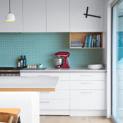 Mid-sized danish u-shaped light wood floor eat-in kitchen photo in Auckland with flat-panel cabinets, white cabinets, blue backsplash, an island, mosaic tile backsplash, a double-bowl sink and stainless steel appliances