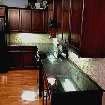 Inspiration for a mid-sized transitional light wood floor open concept kitchen remodel in Kansas City with a double-bowl sink, recessed-panel cabinets, dark wood cabinets, granite countertops, gray backsplash, stone tile backsplash and an island