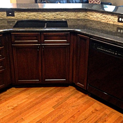 Mid-sized transitional light wood floor open concept kitchen photo in Kansas City with a double-bowl sink, recessed-panel cabinets, dark wood cabinets, granite countertops, gray backsplash, stone tile backsplash and an island