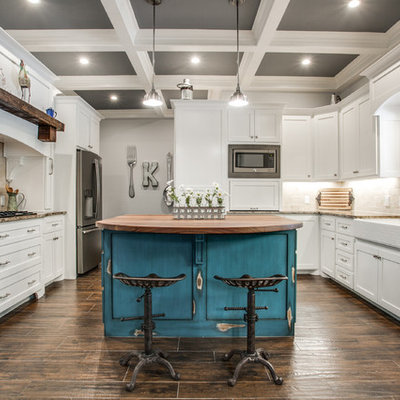 Mid-sized cottage u-shaped medium tone wood floor and brown floor kitchen photo in Dallas with a farmhouse sink, shaker cabinets, white cabinets, beige backsplash, stainless steel appliances, an island, granite countertops and stone tile backsplash