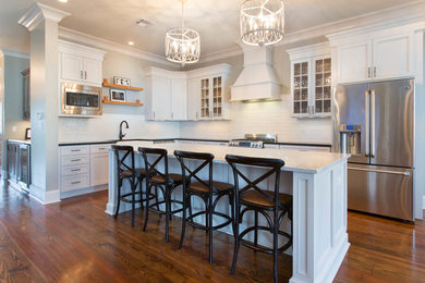 Example of a large transitional l-shaped eat-in kitchen design in New Orleans with shaker cabinets, white cabinets, marble countertops, white backsplash, ceramic backsplash and an island