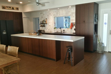 This is an example of a medium sized modern galley kitchen/diner in Orlando with a submerged sink, flat-panel cabinets, dark wood cabinets, concrete worktops, beige splashback, stone tiled splashback, black appliances, cork flooring, an island and brown floors.