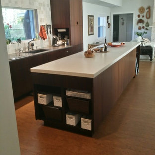 Design ideas for a modern galley open plan kitchen in Orlando with an undermount sink, flat-panel cabinets, dark wood cabinets, concrete benchtops, beige splashback, stone tile splashback, black appliances, cork floors and with island.