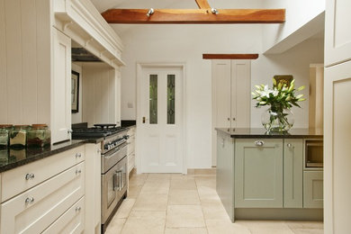 This is an example of a medium sized traditional l-shaped kitchen/diner in Oxfordshire with a single-bowl sink, shaker cabinets, white cabinets, granite worktops, stainless steel appliances, ceramic flooring and an island.