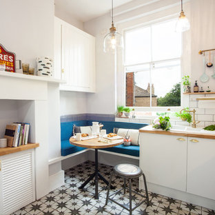 Small eclectic eat-in kitchen in London with a double-bowl sink, flat-panel cabinets, white cabinets, wood benchtops, subway tile splashback, panelled appliances, ceramic floors, no island and multi-coloured floor.