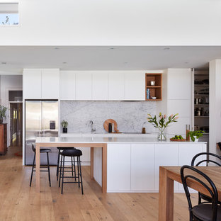Photo of a contemporary galley eat-in kitchen in Adelaide with an undermount sink, flat-panel cabinets, white cabinets, medium hardwood floors, with island, brown floor and white benchtop.