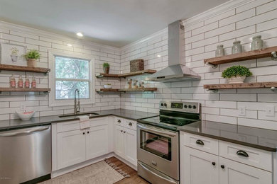 Inspiration for a transitional l-shaped medium tone wood floor and brown floor kitchen remodel in Jacksonville with an undermount sink, shaker cabinets, white cabinets, quartzite countertops, white backsplash, subway tile backsplash, stainless steel appliances and no island