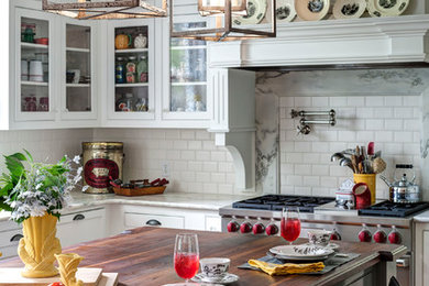 アトランタにある高級なトラディショナルスタイルのおしゃれなアイランドキッチン (ガラス扉のキャビネット、白いキャビネット、大理石カウンター、白いキッチンパネル、サブウェイタイルのキッチンパネル、シルバーの調理設備、無垢フローリング) の写真