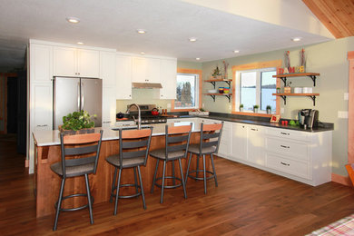 Example of a mid-sized cottage l-shaped vinyl floor and brown floor eat-in kitchen design in Other with shaker cabinets, white cabinets, quartz countertops, stainless steel appliances, an island and gray countertops
