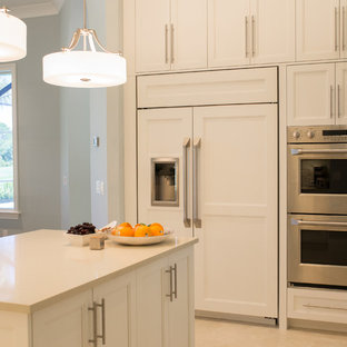 Large beach style l-shaped open plan kitchen in Miami with an undermount sink, recessed-panel cabinets, white cabinets, quartz benchtops, beige splashback, matchstick tile splashback, stainless steel appliances, ceramic floors, with island and beige floor.