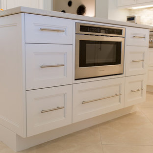 This is an example of a large beach style l-shaped open plan kitchen in Miami with an undermount sink, recessed-panel cabinets, white cabinets, quartz benchtops, beige splashback, matchstick tile splashback, stainless steel appliances, ceramic floors, with island and beige floor.