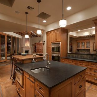 Inspiration pour une grand cuisine américaine traditionnelle avec un électroménager en acier inoxydable, un évier encastré, un placard à porte shaker, des portes de placard en bois brun, une crédence en carrelage de pierre, une crédence multicolore, un îlot central et un sol en carreau de terre cuite.