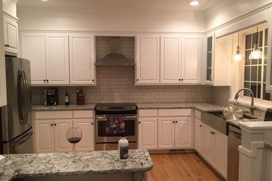 This is an example of a small classic l-shaped enclosed kitchen in Wilmington with raised-panel cabinets, white cabinets, engineered stone countertops, metro tiled splashback, stainless steel appliances, medium hardwood flooring and a breakfast bar.