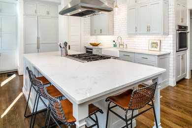 Example of a transitional u-shaped medium tone wood floor eat-in kitchen design in Cincinnati with flat-panel cabinets, white cabinets, granite countertops, white backsplash, ceramic backsplash, colored appliances and an island