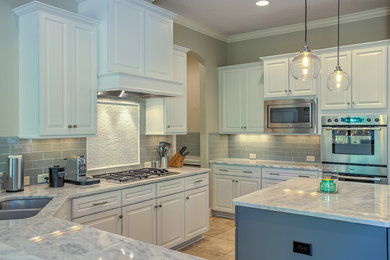 Enclosed kitchen - large transitional u-shaped terra-cotta tile enclosed kitchen idea in Other with raised-panel cabinets, white cabinets, quartz countertops, gray backsplash, subway tile backsplash, stainless steel appliances, an island and an undermount sink