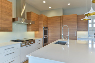Inspiration for a mid-sized contemporary l-shaped light wood floor and beige floor open concept kitchen remodel in Denver with an undermount sink, flat-panel cabinets, light wood cabinets, quartz countertops, glass sheet backsplash, paneled appliances and an island