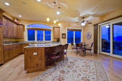 Example of a mountain style light wood floor eat-in kitchen design in Denver with medium tone wood cabinets, stainless steel appliances and an island