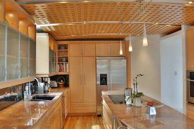Example of a large trendy u-shaped light wood floor eat-in kitchen design in Denver with an undermount sink, flat-panel cabinets, light wood cabinets, granite countertops, black backsplash, glass tile backsplash, stainless steel appliances and an island