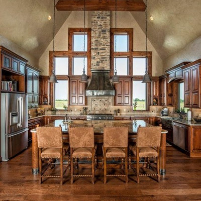 Eat-in kitchen - large rustic u-shaped dark wood floor eat-in kitchen idea in Other with stainless steel appliances, a farmhouse sink, raised-panel cabinets, dark wood cabinets, granite countertops, beige backsplash, stone tile backsplash and an island