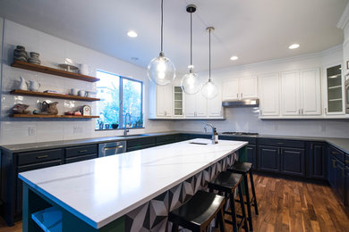 Inspiration for a large transitional u-shaped dark wood floor and brown floor eat-in kitchen remodel in Denver with an undermount sink, raised-panel cabinets, marble countertops, white backsplash, glass tile backsplash, stainless steel appliances, an island and blue cabinets