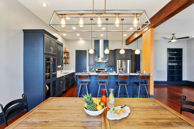 Photo of a large bohemian l-shaped kitchen/diner in New Orleans with a submerged sink, flat-panel cabinets, blue cabinets, engineered stone countertops, blue splashback, ceramic splashback, stainless steel appliances, medium hardwood flooring, an island, brown floors and white worktops.