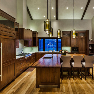 Example of a large mountain style l-shaped medium tone wood floor and brown floor open concept kitchen design in Denver with an undermount sink, shaker cabinets, dark wood cabinets, stainless steel appliances, an island, wood countertops, blue backsplash and glass tile backsplash