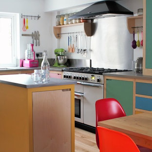 Immagine di una piccola cucina stile americano con lavello da incasso, ante lisce, top in acciaio inossidabile, paraspruzzi a effetto metallico, pavimento in legno massello medio, isola e elettrodomestici bianchi