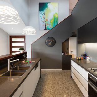 Design ideas for a mid-sized contemporary galley eat-in kitchen in Brisbane with a drop-in sink, flat-panel cabinets, white cabinets, quartz benchtops, metallic splashback, mirror splashback, black appliances, concrete floors, with island, grey floor and brown benchtop.