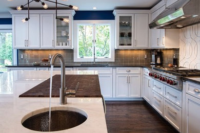 Eat-in kitchen - large transitional u-shaped dark wood floor eat-in kitchen idea in New York with an undermount sink, recessed-panel cabinets, white cabinets, brown backsplash, marble countertops, an island, glass tile backsplash and stainless steel appliances