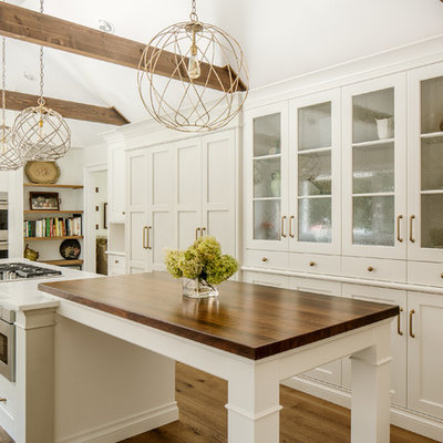 Inspiration for a large cottage u-shaped medium tone wood floor kitchen remodel in New York with shaker cabinets, white cabinets, quartz countertops, stainless steel appliances, a farmhouse sink and an island