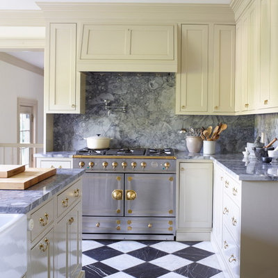Country kitchen photo in New York with a farmhouse sink, shaker cabinets, yellow cabinets, gray backsplash, stainless steel appliances and an island