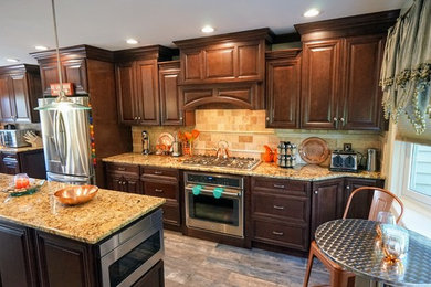 Large transitional l-shaped ceramic tile and brown floor eat-in kitchen photo in New York with an undermount sink, raised-panel cabinets, brown cabinets, granite countertops, beige backsplash, marble backsplash, stainless steel appliances and an island