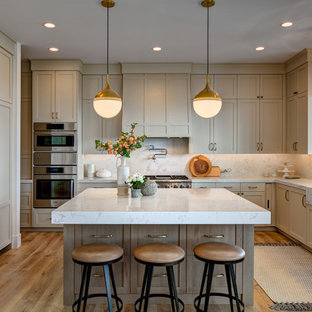 Immagine di una grande cucina classica con ante con riquadro incassato, top in marmo, paraspruzzi in marmo, elettrodomestici in acciaio inossidabile, lavello sottopiano, ante beige, paraspruzzi bianco, pavimento in legno massello medio, pavimento marrone e top bianco