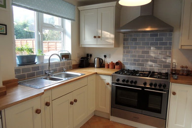 Small farmhouse u-shaped open plan kitchen in Wiltshire with a built-in sink, shaker cabinets, wood worktops, grey splashback, metro tiled splashback, stainless steel appliances and no island.