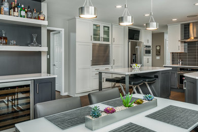 Small l-shaped medium tone wood floor and brown floor enclosed kitchen photo in Other with an undermount sink, shaker cabinets, gray cabinets, quartz countertops, gray backsplash, glass tile backsplash, stainless steel appliances, an island and white countertops
