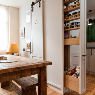 Inspiration for a small contemporary l-shaped kitchen pantry in London with a single-bowl sink, flat-panel cabinets, beige cabinets, granite worktops, green splashback, ceramic splashback, stainless steel appliances, light hardwood flooring, no island, brown floors and black worktops.