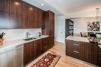 Example of a trendy u-shaped open concept kitchen design in Tampa with an undermount sink, flat-panel cabinets, dark wood cabinets, solid surface countertops, white backsplash and stainless steel appliances