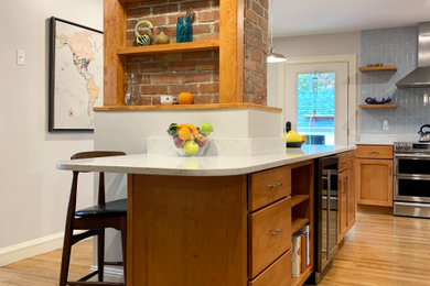 Large classic u-shaped kitchen/diner in Boston with a submerged sink, recessed-panel cabinets, medium wood cabinets, quartz worktops, stainless steel appliances, medium hardwood flooring, an island and white worktops.