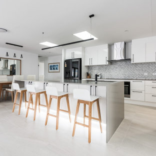 Photo of a large contemporary galley eat-in kitchen in Gold Coast - Tweed with an undermount sink, white cabinets, quartz benchtops, grey splashback, marble splashback, black appliances, ceramic floors, with island, beige floor, grey benchtop and flat-panel cabinets.