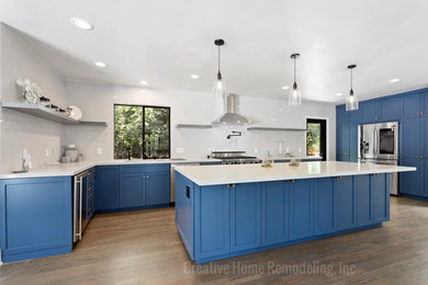 Inspiration for a large contemporary u-shaped light wood floor and brown floor kitchen remodel in Los Angeles with an undermount sink, shaker cabinets, blue cabinets, quartzite countertops, stainless steel appliances, an island and white countertops