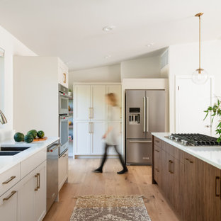 Inspiration for a large contemporary single-wall open plan kitchen in Seattle with a double-bowl sink, shaker cabinets, grey cabinets, quartz benchtops, white splashback, stainless steel appliances, light hardwood floors, with island, yellow floor and white benchtop.