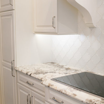 Example of a mid-sized transitional u-shaped medium tone wood floor and brown floor open concept kitchen design in Orlando with an undermount sink, white cabinets, granite countertops, white backsplash, paneled appliances, an island, raised-panel cabinets and ceramic backsplash