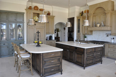 Example of a classic l-shaped kitchen design in San Diego with a farmhouse sink, recessed-panel cabinets, medium tone wood cabinets, white backsplash, paneled appliances and two islands