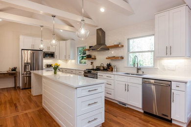 Example of a trendy l-shaped medium tone wood floor and brown floor open concept kitchen design in Los Angeles with a single-bowl sink, white cabinets, white backsplash, stainless steel appliances, an island, white countertops, shaker cabinets and porcelain backsplash