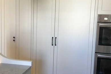 Example of a mid-sized classic medium tone wood floor kitchen pantry design in New York with recessed-panel cabinets, granite countertops, stainless steel appliances and an island