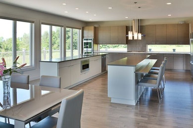 Example of a trendy light wood floor kitchen design in Cleveland with gray cabinets, window backsplash, stainless steel appliances and two islands