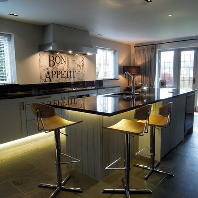 Example of a trendy galley kitchen design in Surrey with an undermount sink, shaker cabinets, white cabinets and glass sheet backsplash