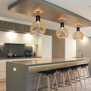Design ideas for a large contemporary single-wall open plan kitchen in Sydney with an undermount sink, flat-panel cabinets, white cabinets, quartz benchtops, grey splashback, black appliances, porcelain floors, with island, grey floor and grey benchtop.