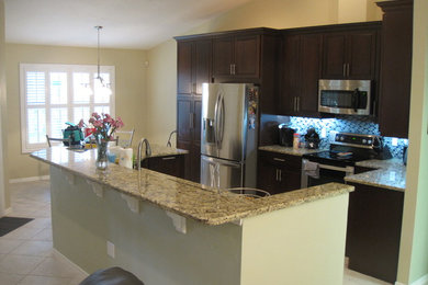 Mid-sized minimalist l-shaped ceramic tile kitchen pantry photo in Miami with an undermount sink, recessed-panel cabinets, dark wood cabinets, granite countertops, multicolored backsplash, glass tile backsplash, stainless steel appliances and an island