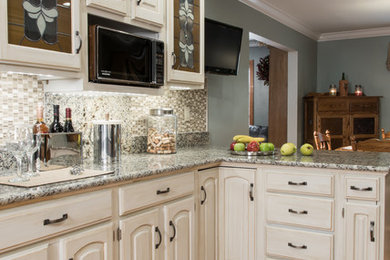 This is an example of a traditional kitchen pantry in St Louis with a built-in sink, distressed cabinets, granite worktops, multi-coloured splashback, glass tiled splashback and medium hardwood flooring.